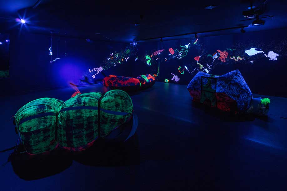 <b>Title: </b>Atrophic Chain, In collaboration with Attua Aparicio from Silo Studio<br /><b>Medium: </b>UV lights, Mouth blown Uranium glass, welded metal structures, tyed dyed ripstock inflatables, mural.<br /><b>Size: </b>Dimensions variable